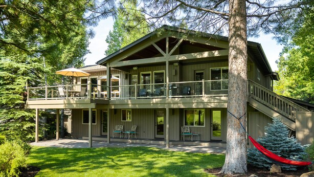 A two-story wooden house with a balcony, a covered patio, and a red hammock. - 18 White Elm, 3 King Suites+Bunk Room! On 14th Green, Hot Tub, Bikes, 10 Passes (Sunriver)