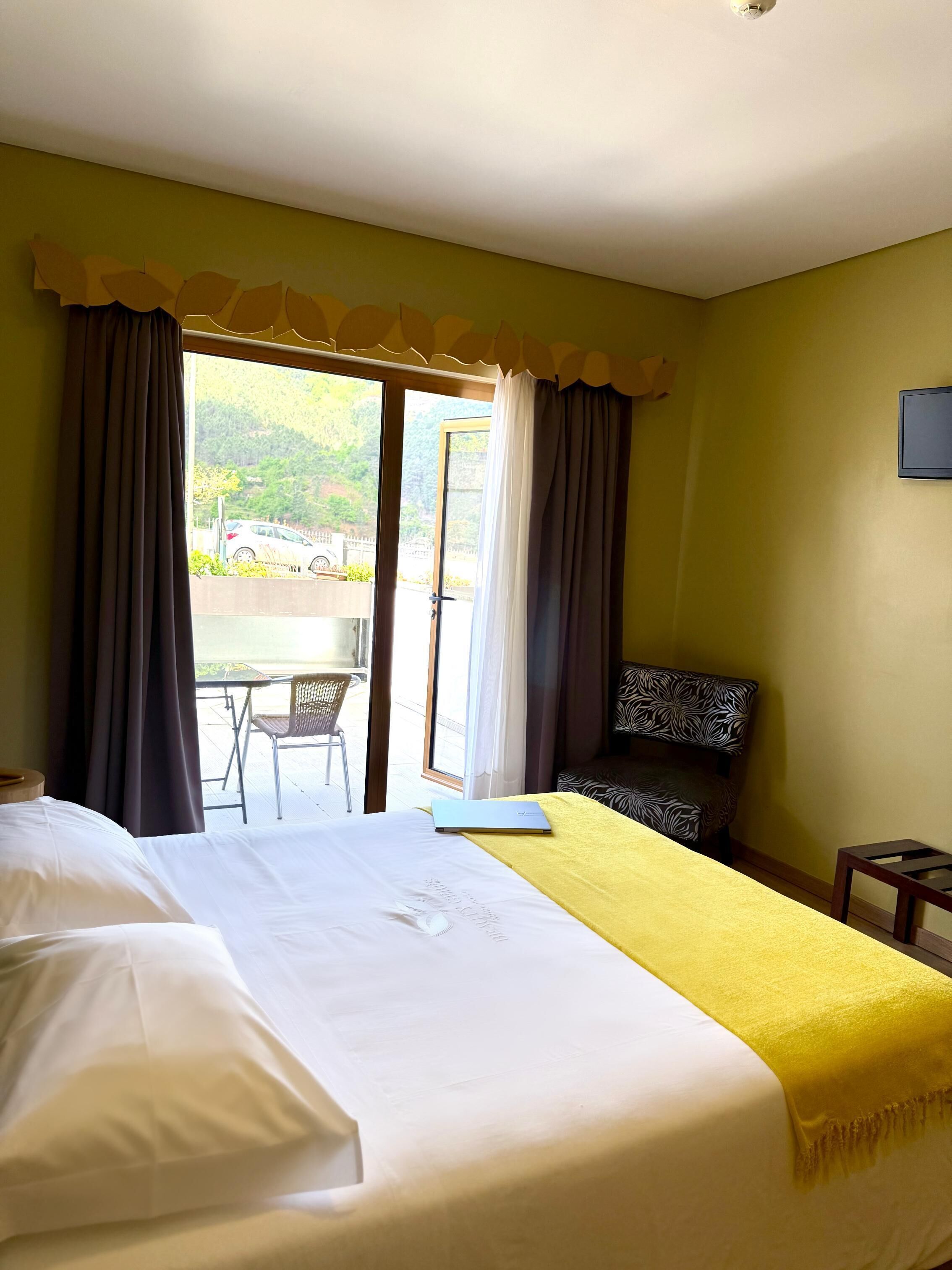 A hotel room with a bed, a desk, a chair, and a view of the outdoors.