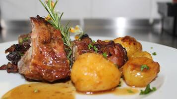 Une assiette de nourriture comprenant de la viande rôtie et des pommes de terre.