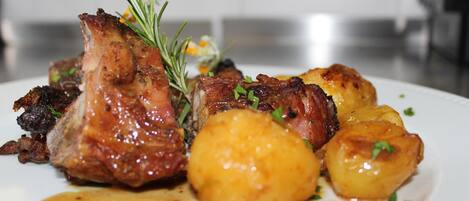 Une assiette de nourriture comprenant de la viande rôtie et des pommes de terre.