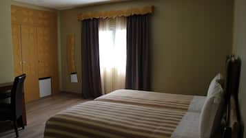 A hotel room with a bed, a desk, and a wardrobe.