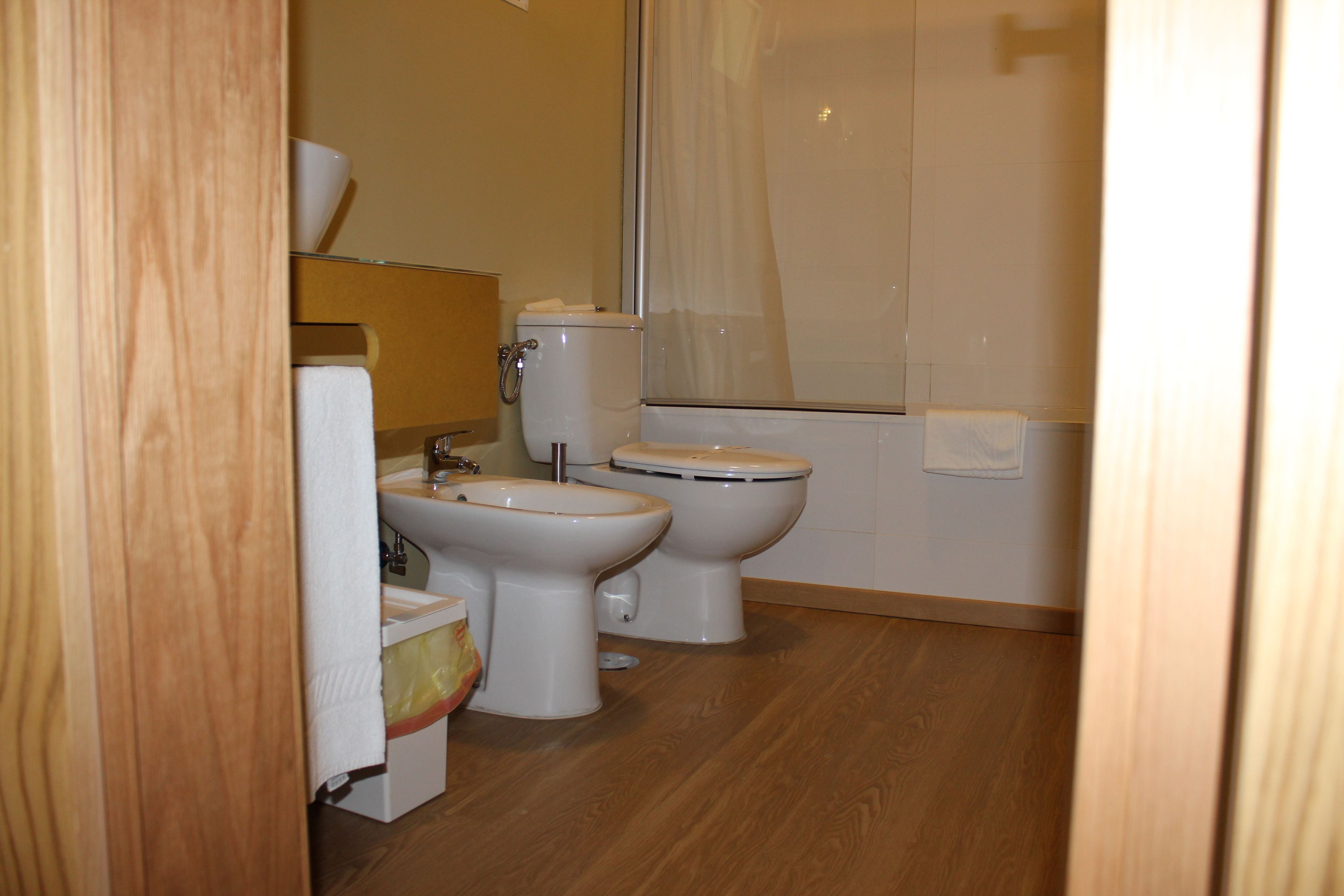 Une salle de bain avec deux toilettes, un lavabo et un espace douche.