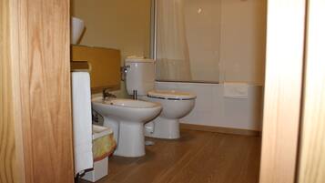 Une salle de bain avec deux toilettes, un lavabo et un espace douche.