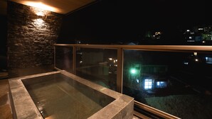A modern spa area with a stone wall and a glass-enclosed hot tub.