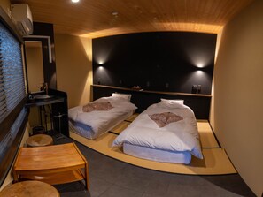 A room with two beds, a small wooden table, a sink, and a mirror. - Shirakaba (Nozawaonsen)