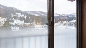 A view from a window overlooking a town with buildings and snow-covered hills.