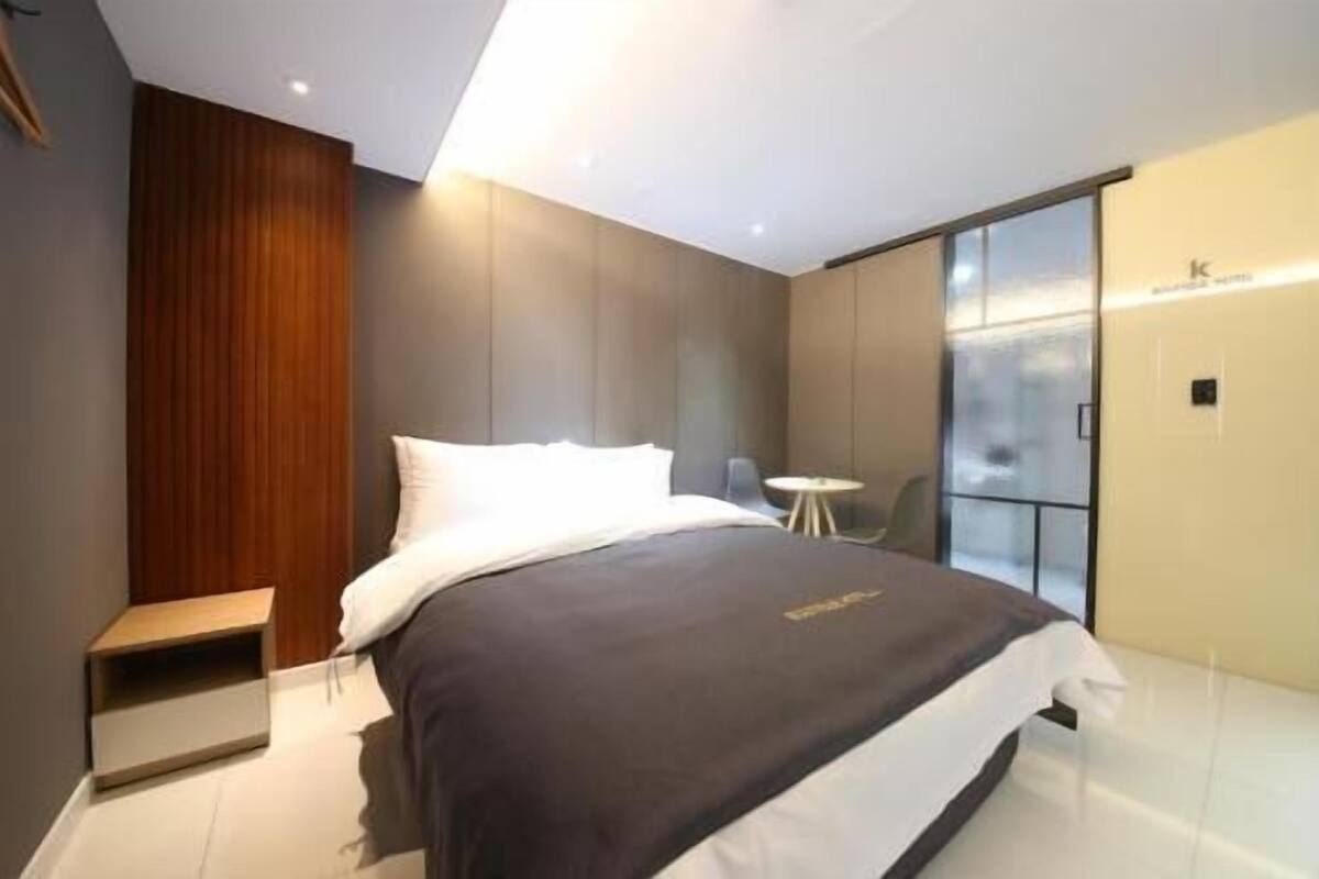 A modern hotel room with a bed, bedside table, and a small round table.