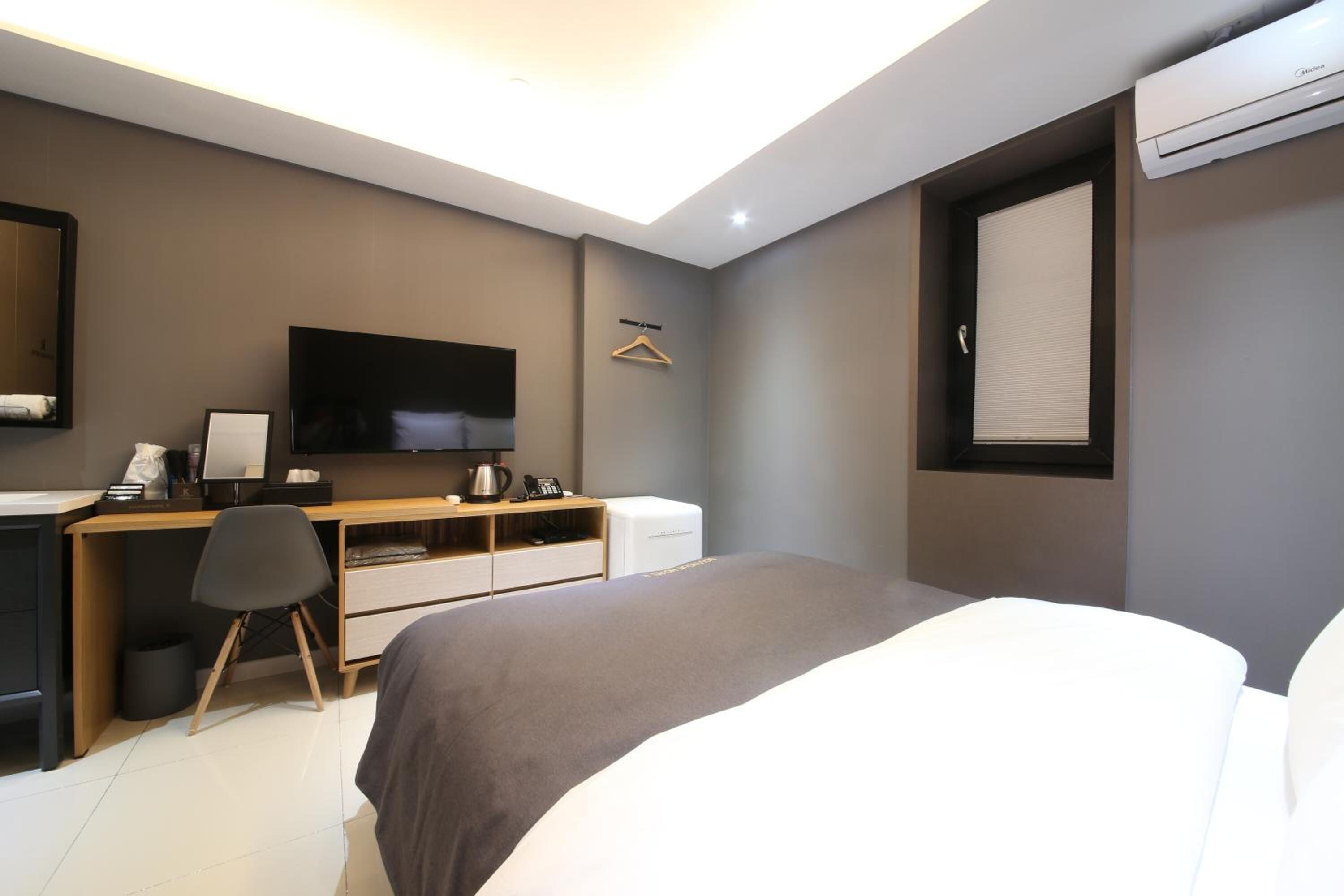 Une chambre d’hôtel moderne équipée d’un lit, d’un bureau, d’une chaise, d’une télévision et d’un appareil de climatisation.