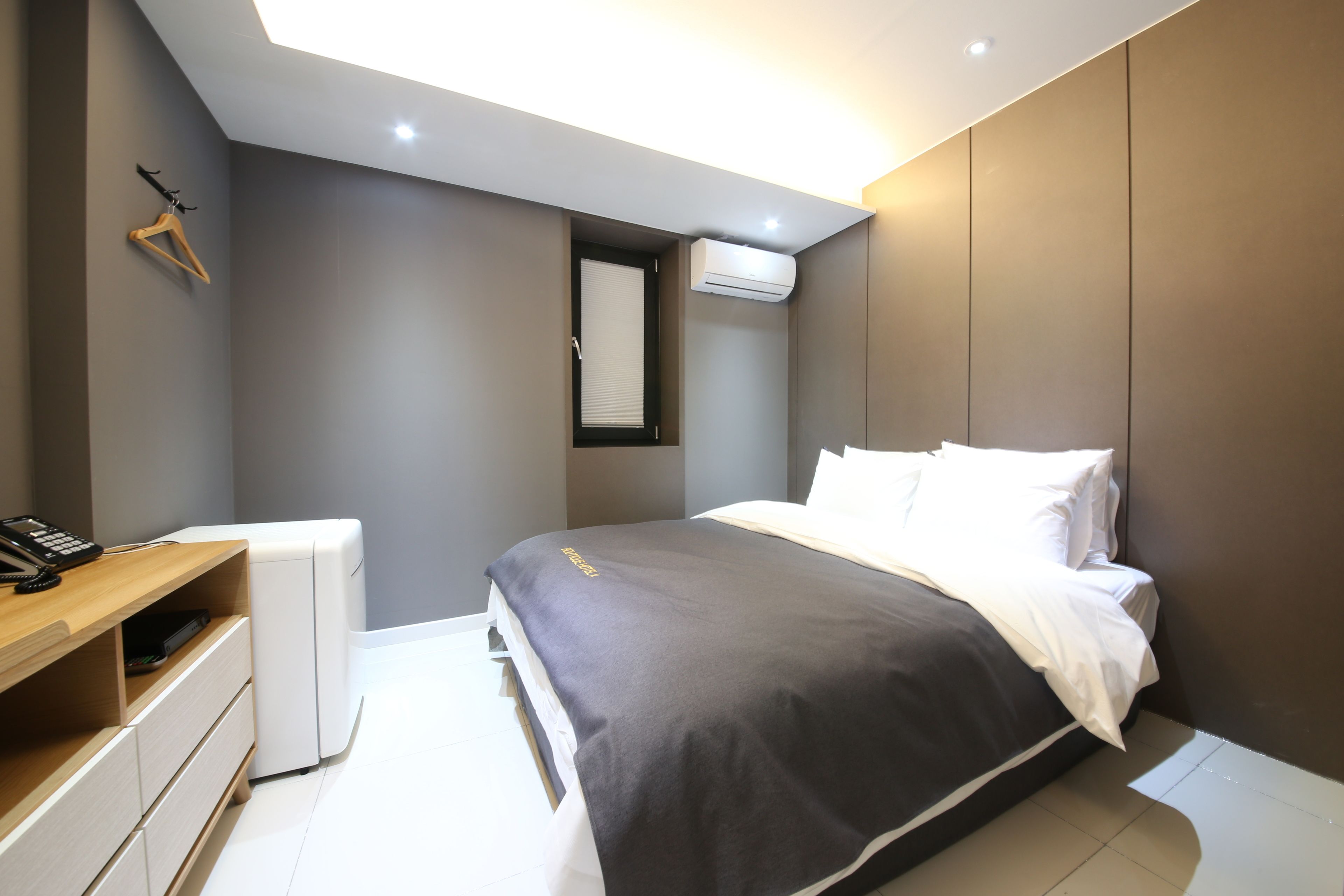 A modern bedroom with a bed, bedside table, and a wardrobe.