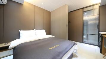 A modern hotel room with a bed, a desk, and a sliding door leading to a bathroom.