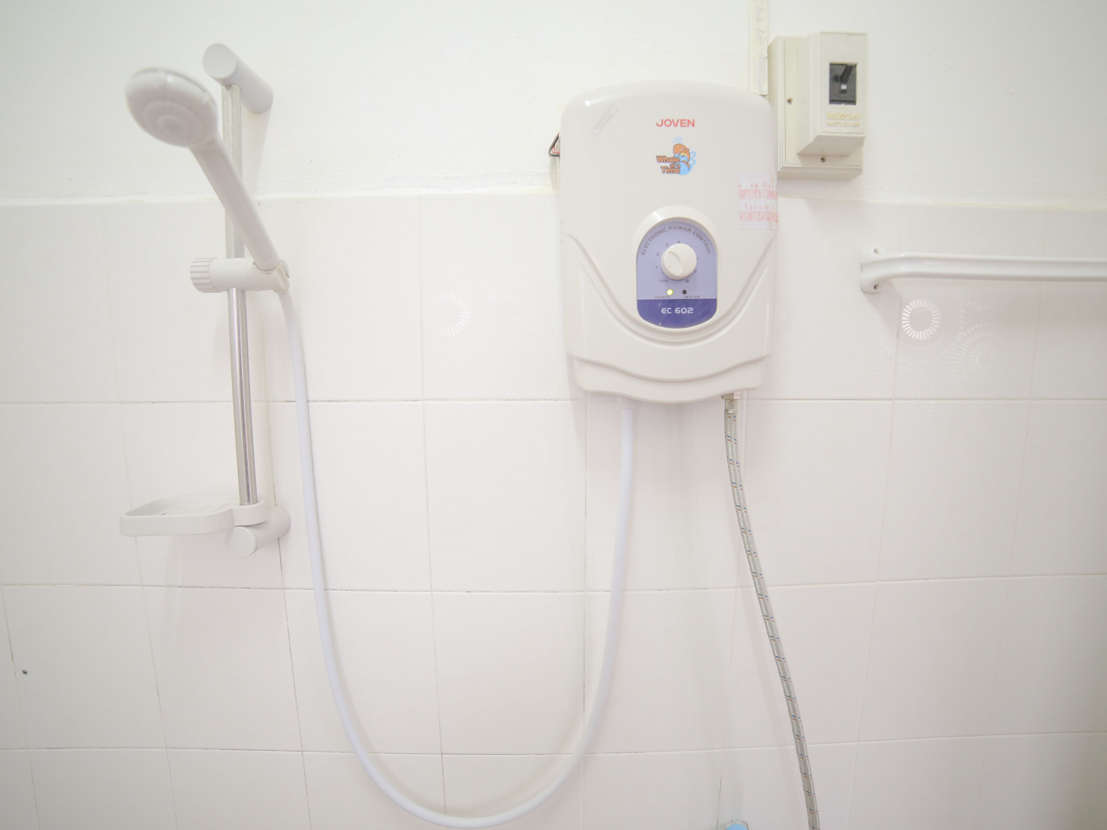 Ducha con cabezal de ducha de mano y panel de control en la pared.