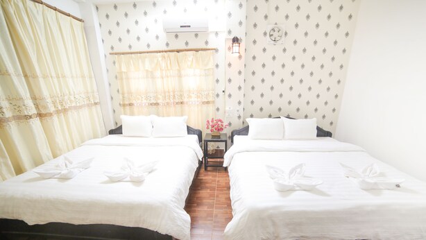 A hotel room with two beds, a nightstand, a lamp, and a window with curtains. - Maylay Guesthouse (Vang Vieng)