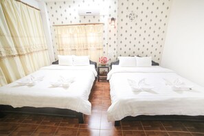 Una habitación de hotel con dos camas, una mesita de noche, una lámpara y una ventana con cortinas.
