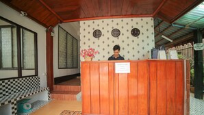 A reception area with a wooden desk, a clock, and a sign indicating free internet WiFi. - Maylay Guesthouse (Vang Vieng)