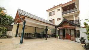 A two-story building with a covered patio area, a balcony on the upper floor, and a sign indicating it is a guest house. - Maylay Guesthouse (Vang Vieng)