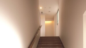 A staircase with wooden steps and a wooden handrail, leading to a landing with a light source. - Kanazawa TAMARUYA (Kanazawa)