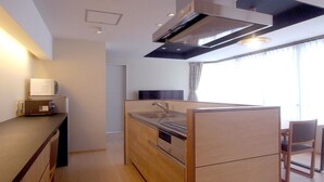 A compact kitchen with a built-in oven, a sink, and a microwave. There is a dining area with a chair and a table. - Kanazawa TAMARUYA (Kanazawa)