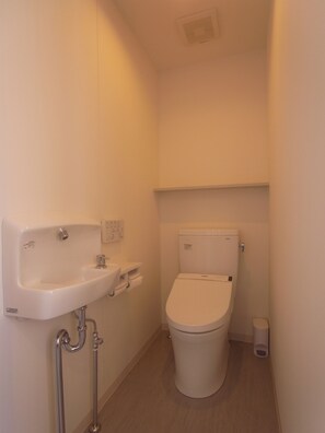 A small, clean bathroom with a white sink, toilet, and a trash bin. - Kanazawa TAMARUYA (Kanazawa)