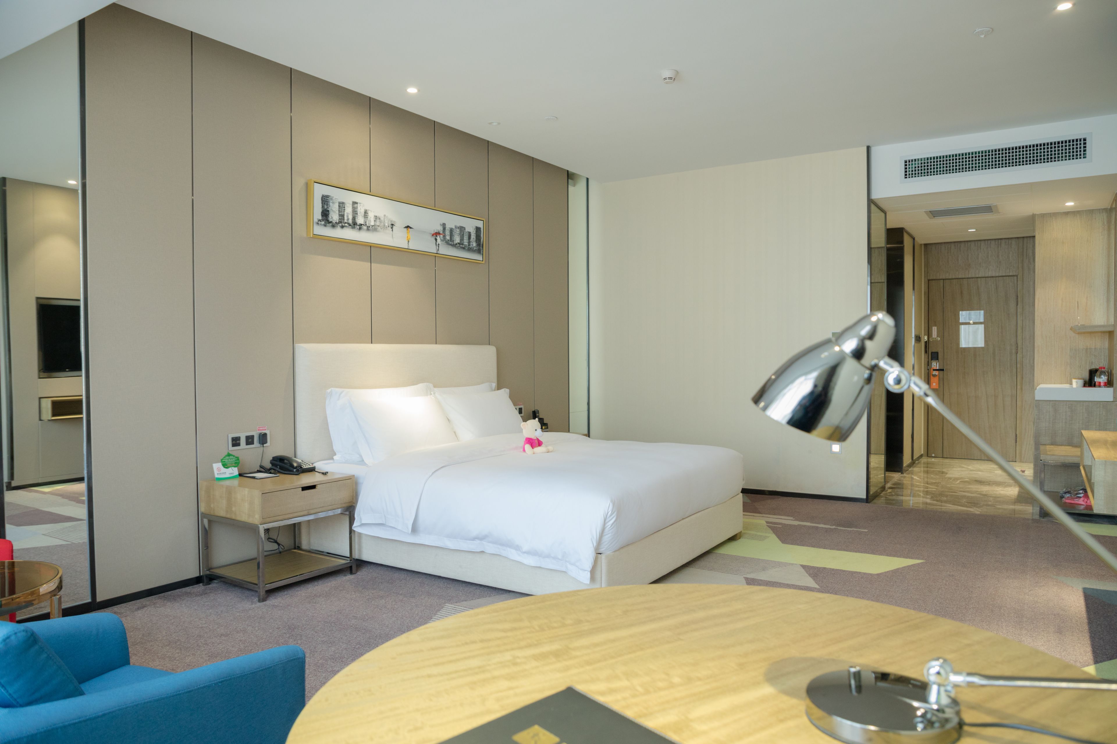 Une chambre d’hôtel avec un lit, un bureau doté d’une lampe, une chaise et une petite table.