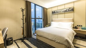 A hotel room with a large bed, a desk, a coat rack, and a city view through the window. - Rongjin Hotel Shenzhen (Shenzhen)