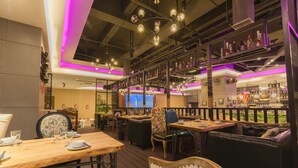 A restaurant with wooden tables and chairs, a bar area with shelves of bottles, and a balcony with a view. - Rongjin Hotel Shenzhen (Shenzhen)