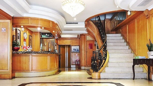 Un vestíbulo espacioso con suelo de mármol, paneles de madera, una escalera y una zona de bar.