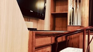 Una habitación compacta con televisión integrada, muebles de madera y un espejo.