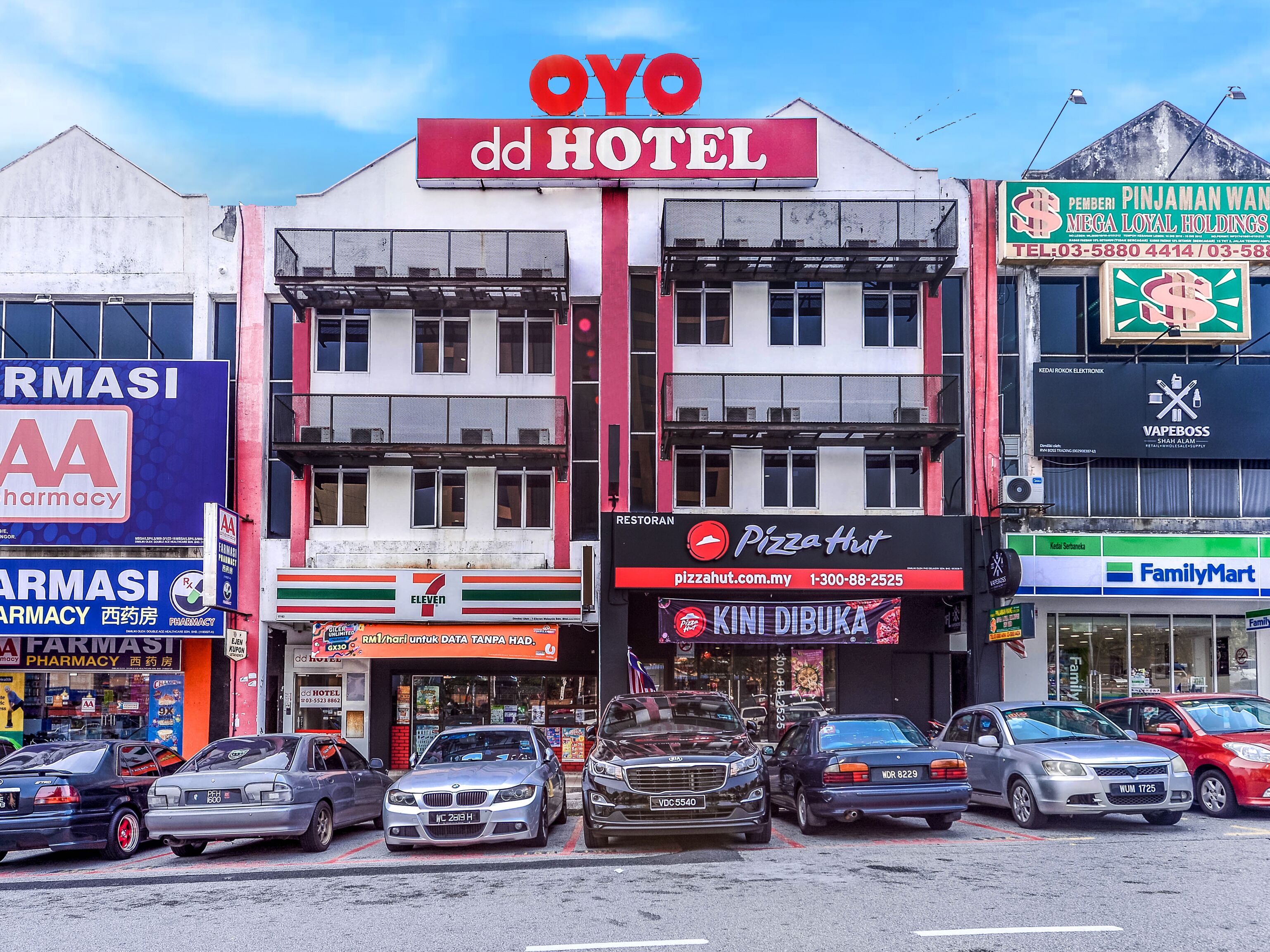 A hotel with a prominent sign, a pharmacy, a 7-Eleven, a Pizza Hut, and a FamilyMart.
