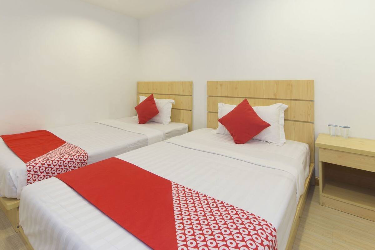 Ein Hotelzimmer mit zwei Einzelbetten, jeweils mit einer rot-weißen Bettdecke, weißen Kissen und einem hölzernen Kopfteil.