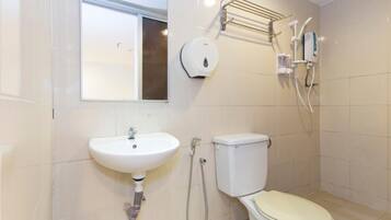Et badeværelse med vask, toilet og bruseområde.
