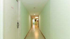 Un pasillo largo y estrecho con paredes verde claro y suelo de baldosas blancas.