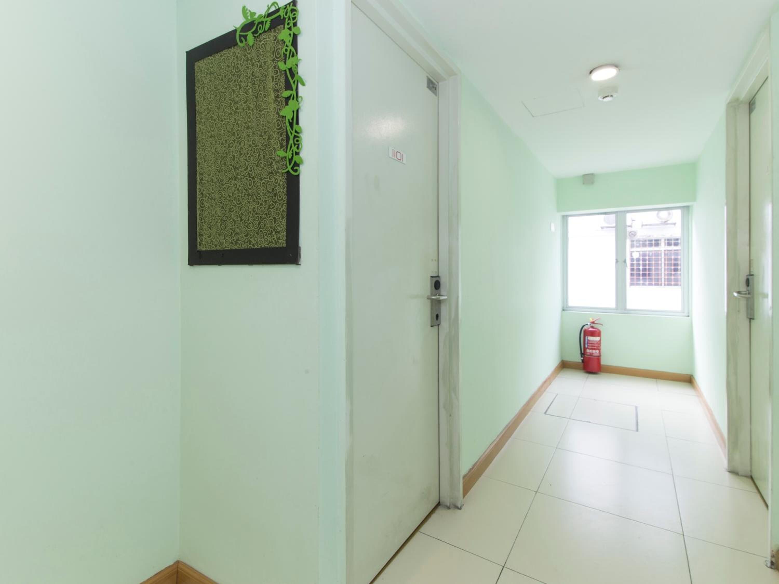 A hallway with a door, a window with a fire extinguisher, and a patterned wall decoration.