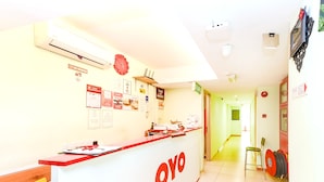 Una recepción con el logotipo 'OYO', un reloj y varios carteles informativos en la pared.