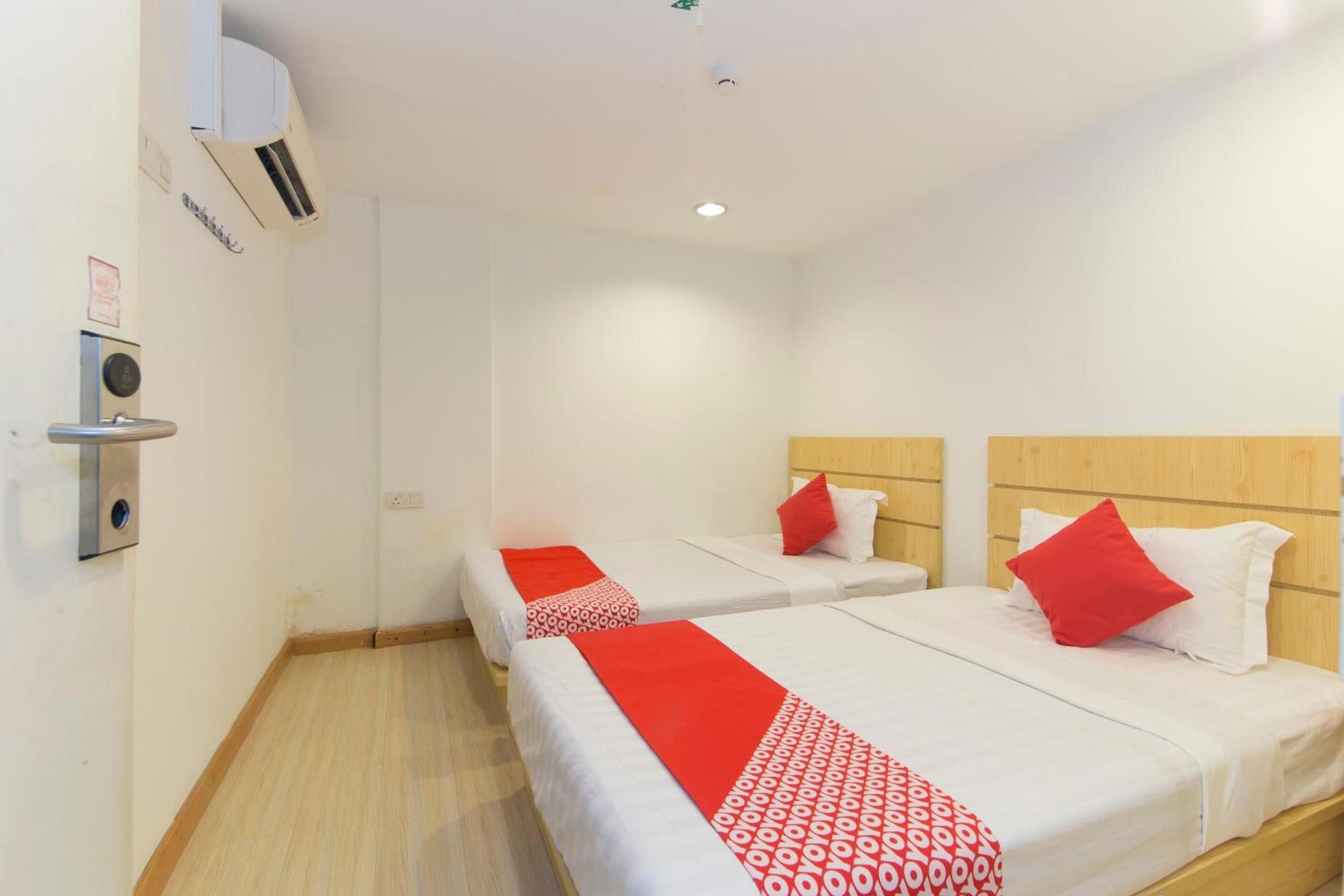 A hotel room with two beds, each with a red and white patterned bedspread, and a wooden headboard.