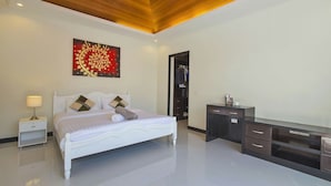 A modern bedroom with a white bed, a nightstand, a desk, and a large artwork on the wall. - Oazza Villa (Rawai)