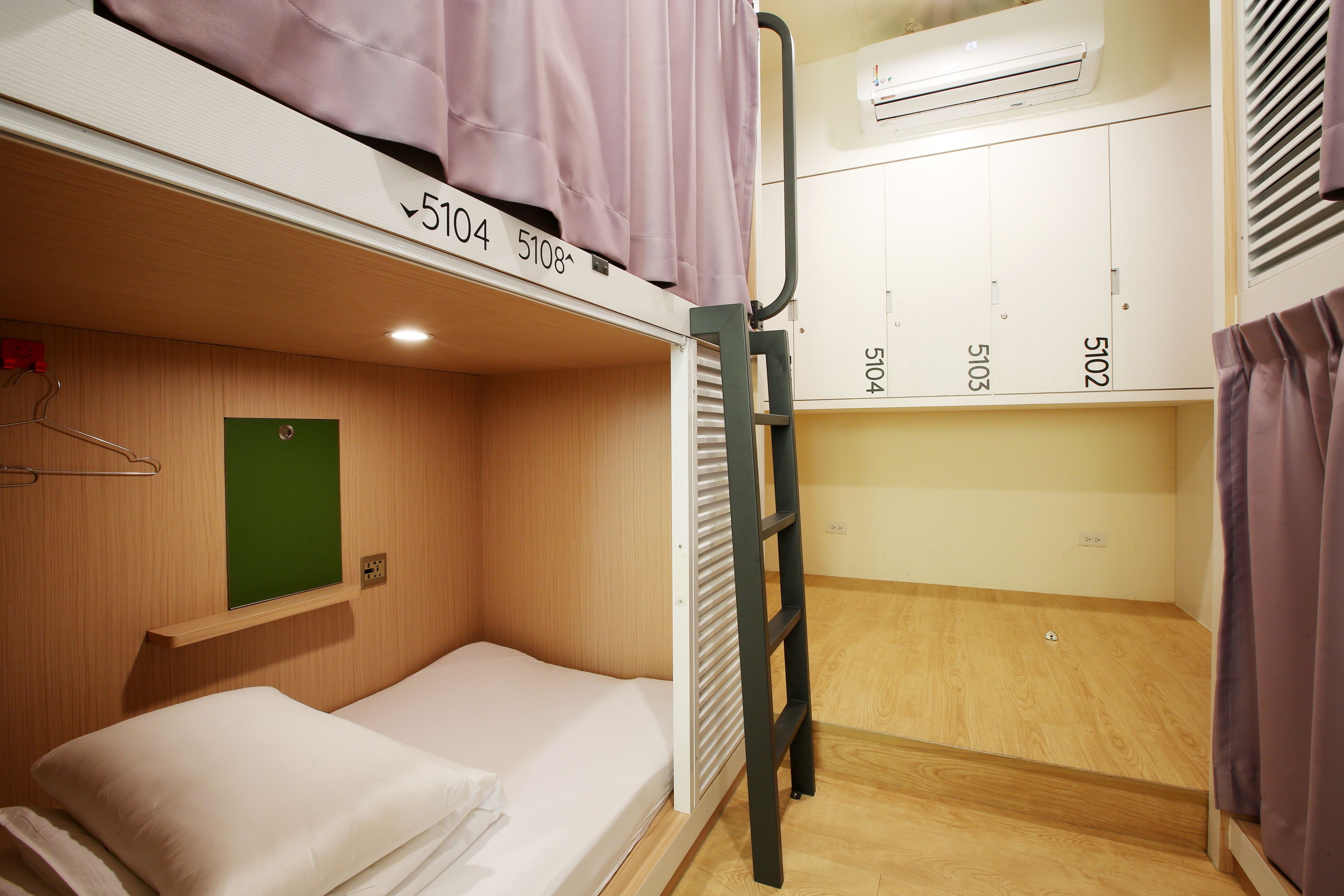 A bunk bed room with a green door, a small shelf, and a ladder.