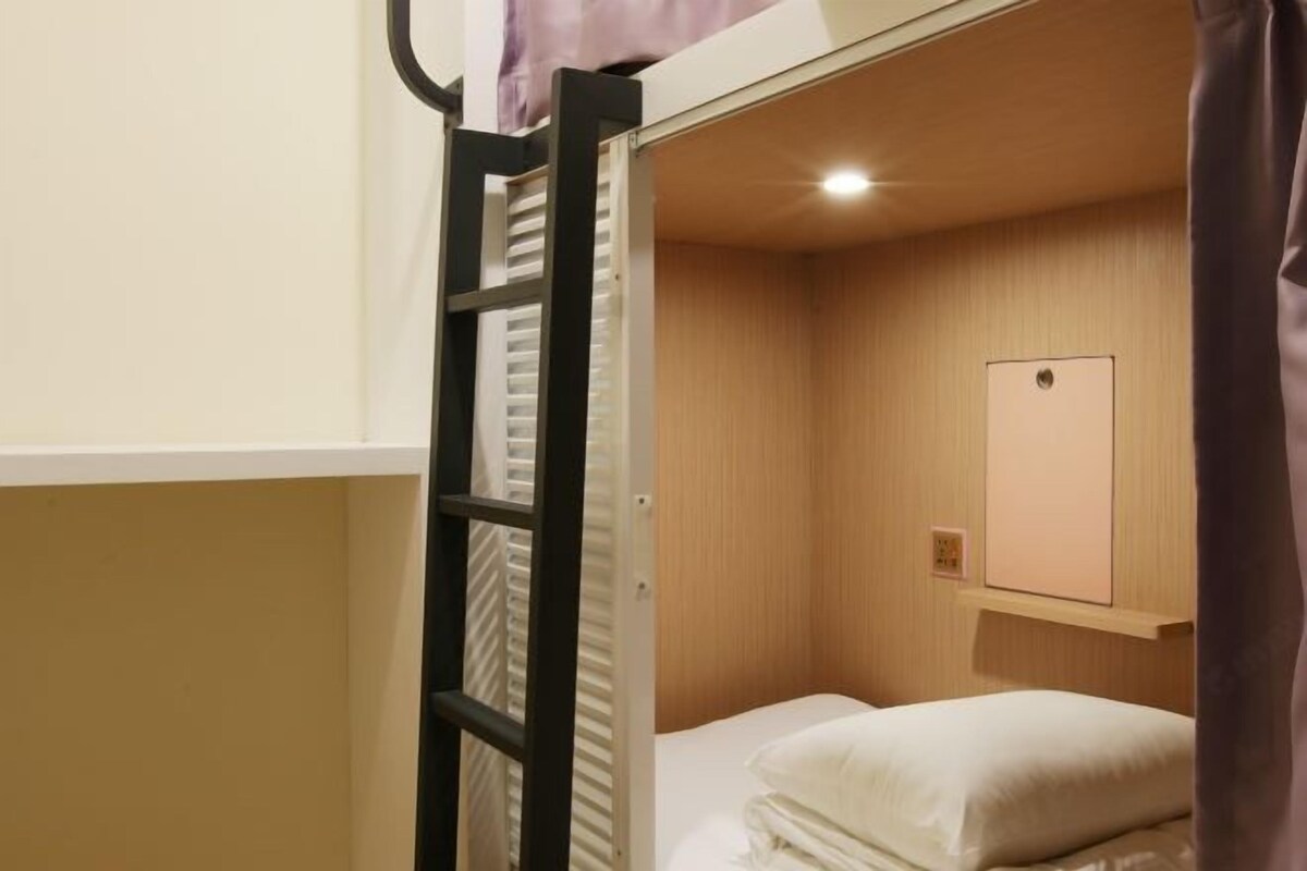 A bunk bed room with a wooden wall, a small shelf, and a light fixture.