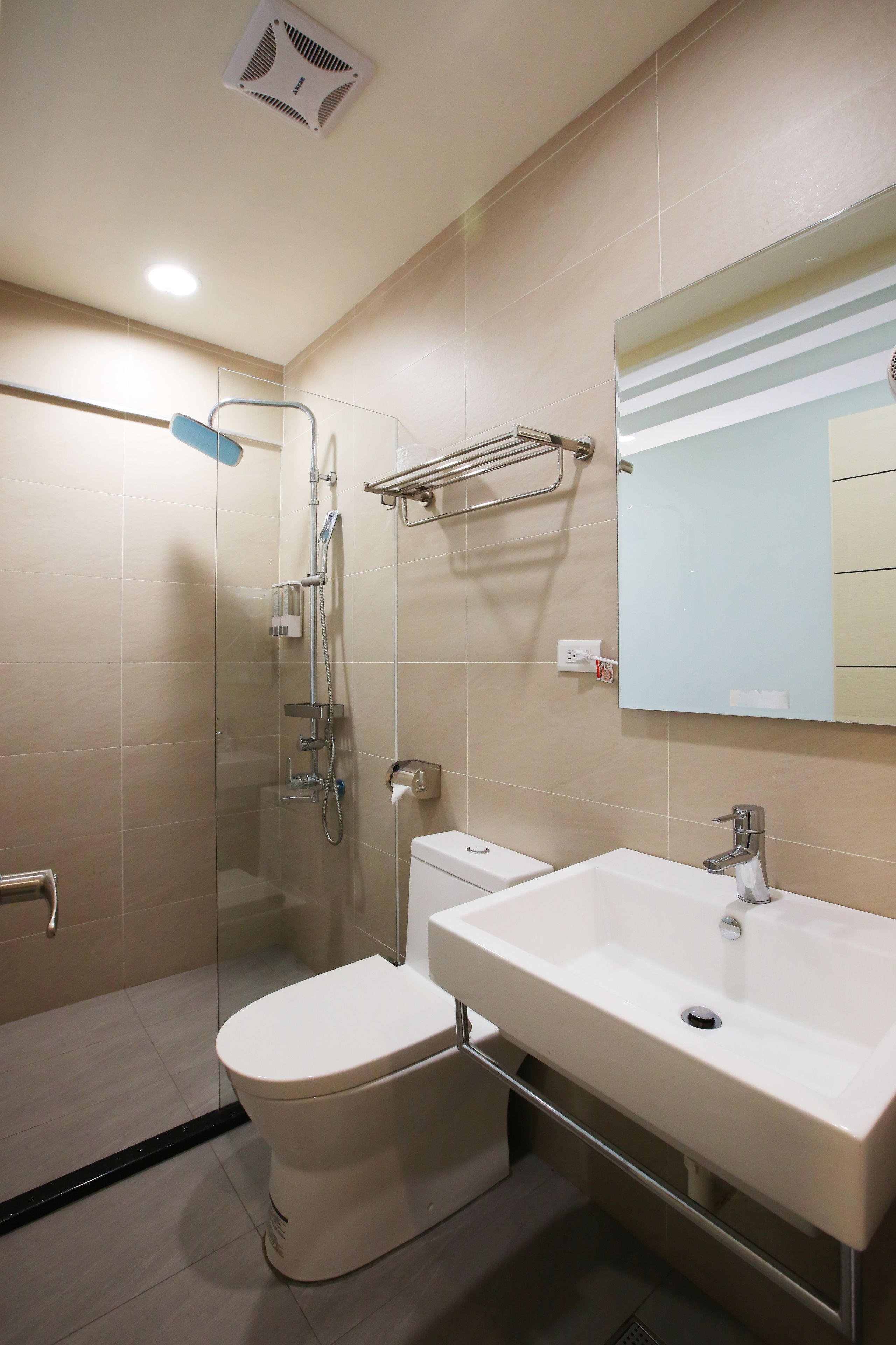 A modern bathroom with a glass-enclosed shower, a white toilet, and a large sink with a mirror above it.