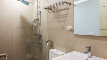A modern bathroom with a glass-enclosed shower, a white toilet, and a large sink with a mirror above it.