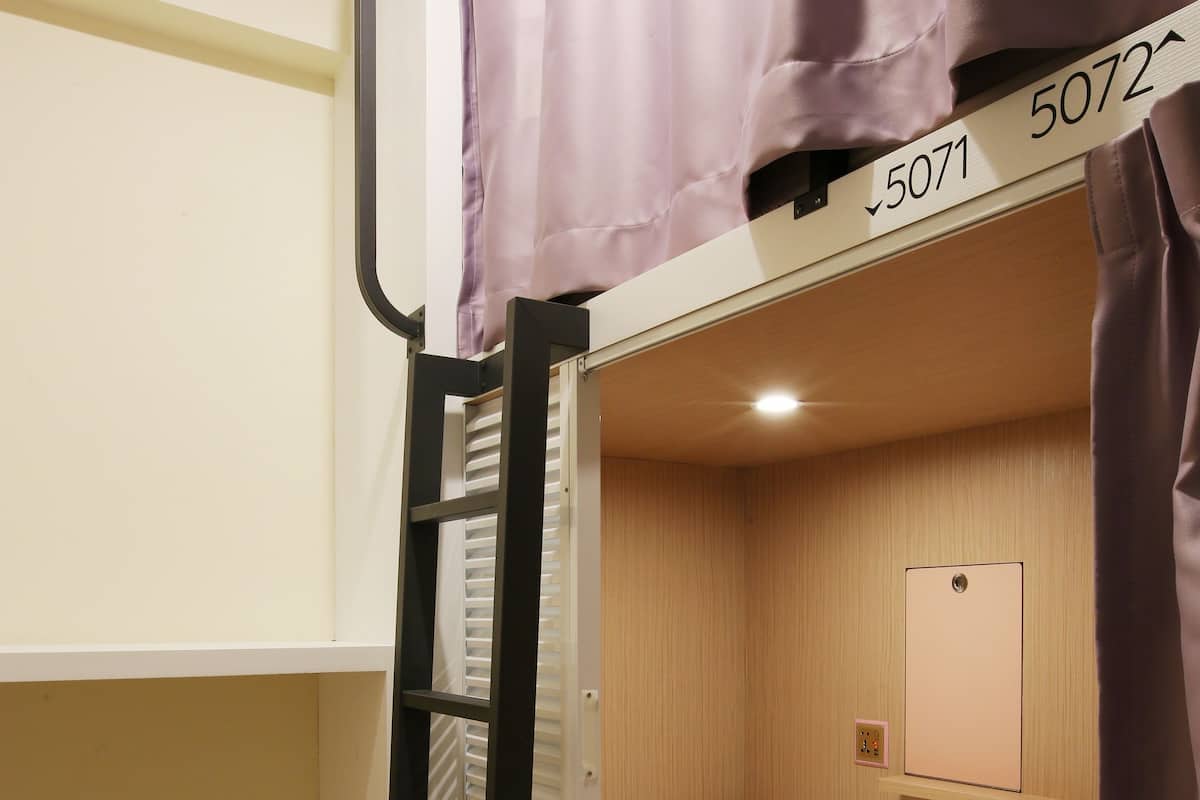A bunk bed with a ladder, a small shelf with a mirror, and a number sign above the bed.