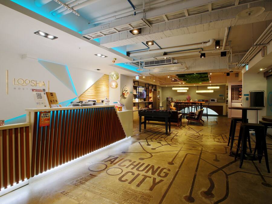 Un hall d’hôtel moderne comprenant un comptoir d’accueil, une table de billard et un espace bar.