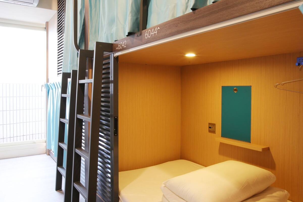 A bunk bed room with a window, a wall-mounted shelf, and a door.