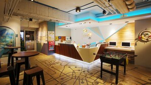 A modern hotel lobby with a foosball table, bar area, and a reception desk. - Loosha Hostel (Taichung)