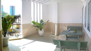 A balcony with a green bench, a potted plant, and a table with a bottle and a plant. - Homestay 78 (Ho Chi Minh City)