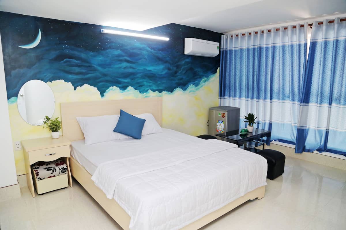 A bedroom with a bed, night sky mural, air conditioning unit, curtains, and a small table with a plant.