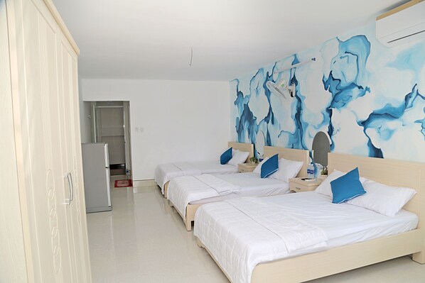 Habitación de hotel con tres camas, un armario, un espejo y una pared con arte abstracto.