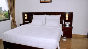 A neatly made bed with white bedding, a wooden headboard, two bedside tables with lamps, and a framed picture on the wall. - Tam Coc Victoria Hotel (Nam Hoa Lu)