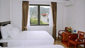 A hotel room with two beds, a dining table with chairs, and a window with curtains. - Tam Coc Victoria Hotel (Nam Hoa Lu)