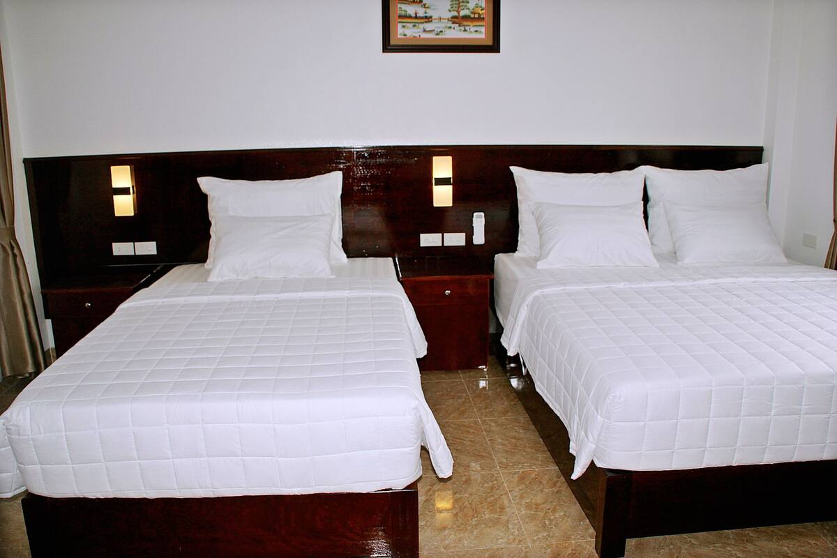 Two single beds with white bedding, wooden headboards, and bedside tables with lamps.