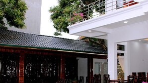 A pool table in a courtyard with a tiled floor, surrounded by wooden chairs and tables. - Tam Coc Victoria Hotel (Nam Hoa Lu)
